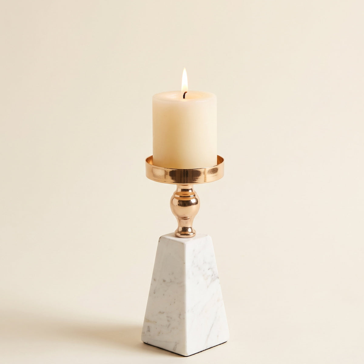 Aurum marble candle holder with a gold dish holding a lit pillar candle, on a cream background, Style Room