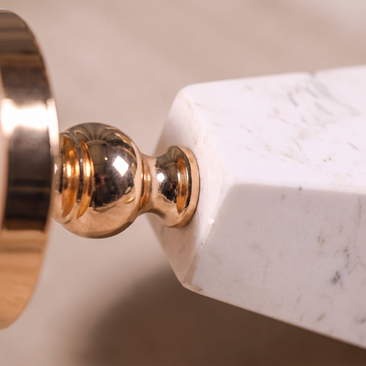 Close detail of the gold stem meeting the white marble pyramid base of the Aurum holder, Style Room