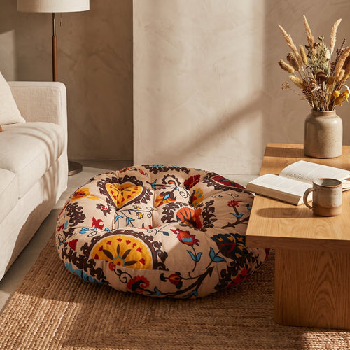 Cream folk-print round floor cushion beside an oak coffee table on a jute rug, Style Room