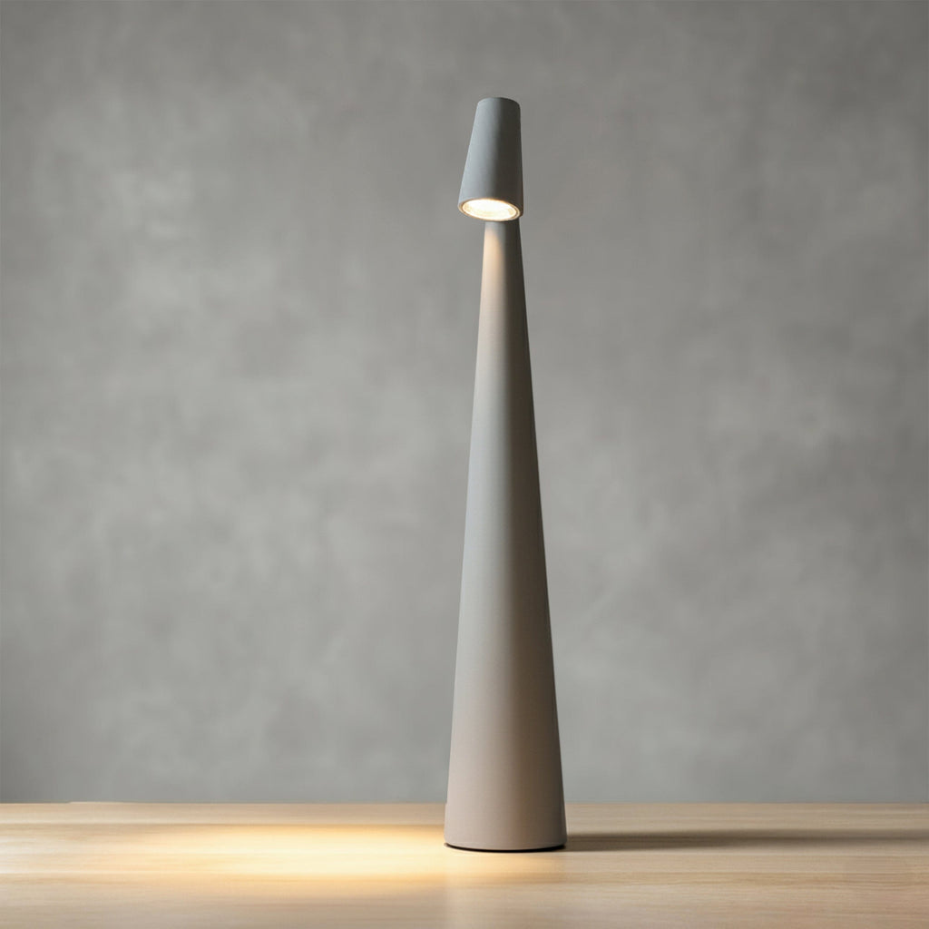 Bexley table lamp in grey, tapered aluminium cone lit on a wooden surface