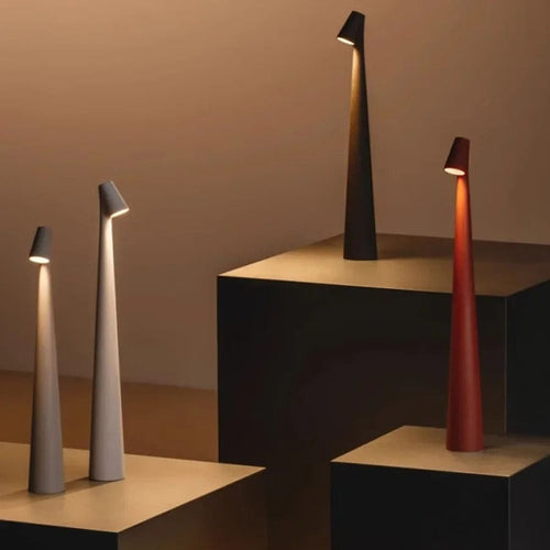 Four Bexley table lamps in grey, white, black and red arranged on stepped plinths