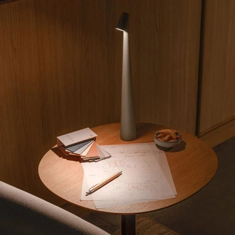 Bexley table lamp lit on a round side table with a notebook and pencil