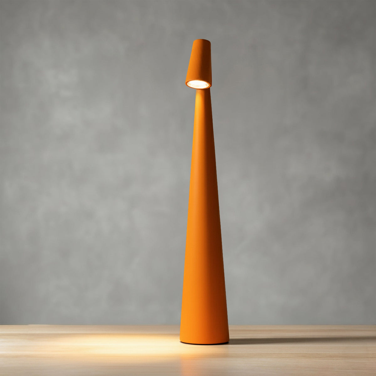 Bexley table lamp in orange, lit against a grey wall