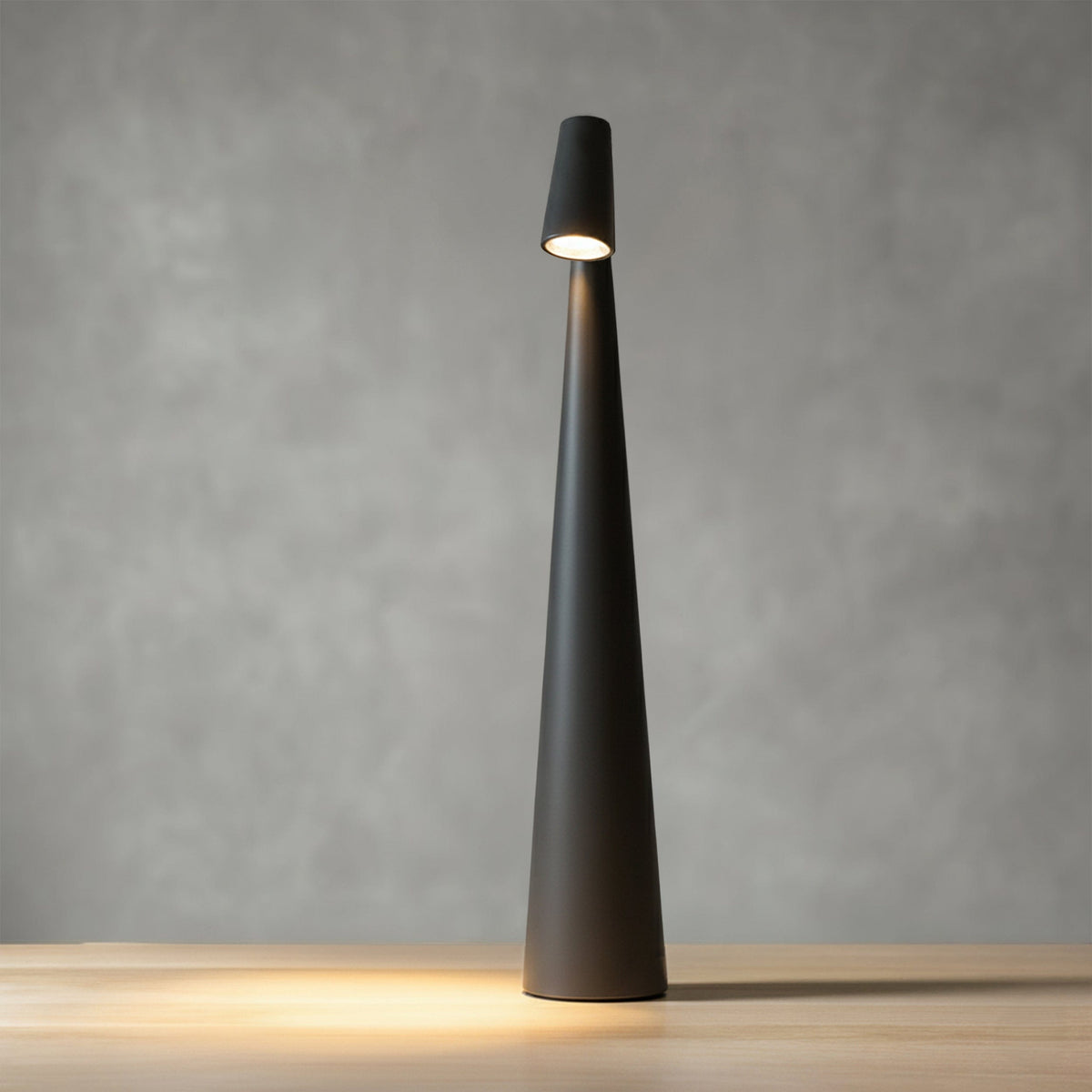 Bexley table lamp in black, lit against a grey wall