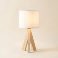 Birk table lamp with a solid wood tripod base and white drum shade, lit, on a cream background, Style Room
