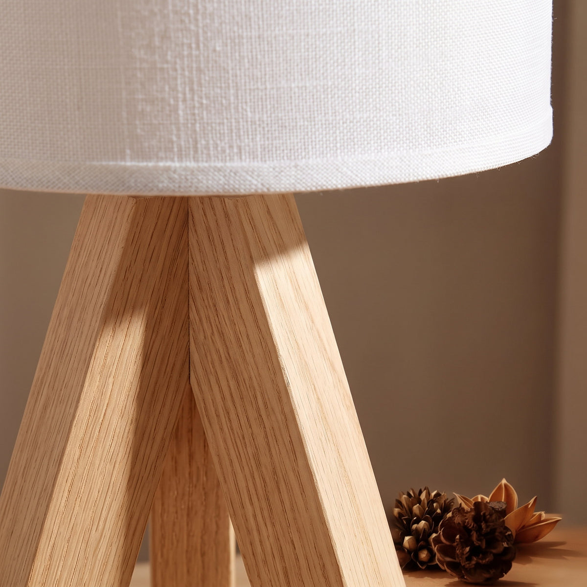 Close detail of the Birk lamp where the three solid wood legs meet under the linen drum shade, Style Room