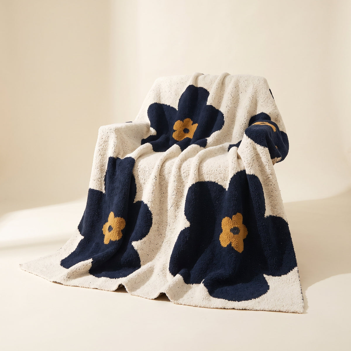 Bloom navy and cream knitted blanket with gold-centred daisy motifs, Style Room