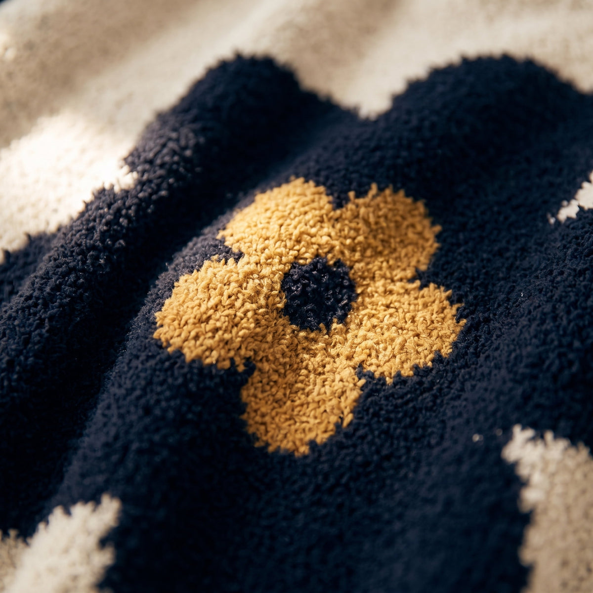 Close-up of a gold-centred daisy motif on the Bloom knitted blanket, Style Room