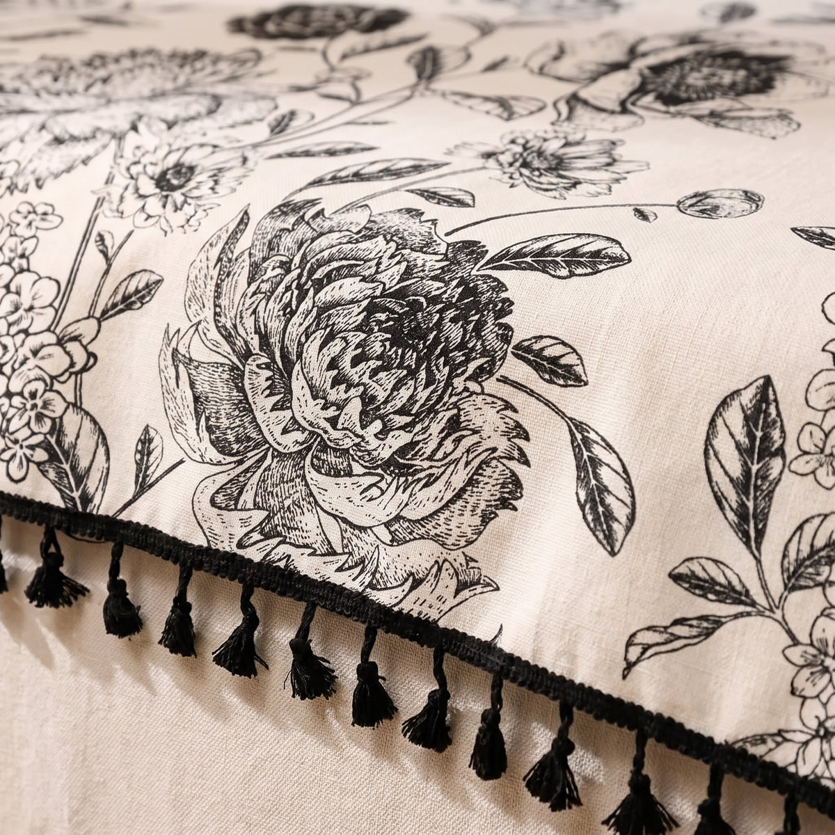 Close-up of the black floral print and tassel fringe of the Blythe tablecloth, Style Room