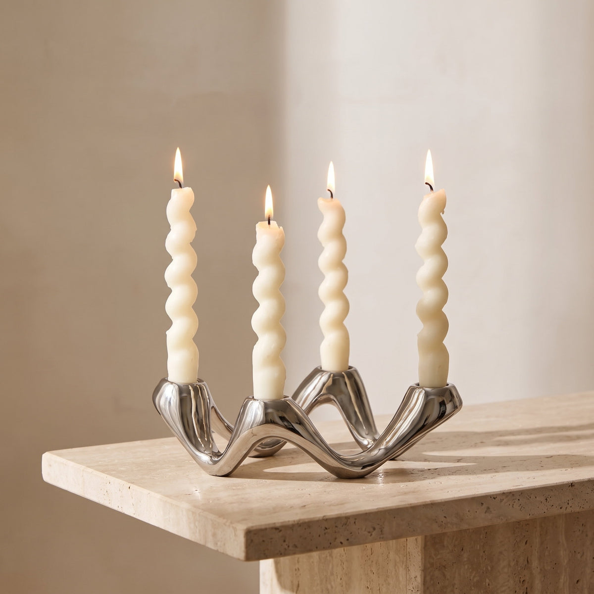 Celora silver candle holder lit on a travertine console, Style Room
