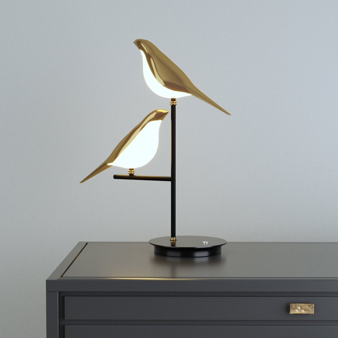 Cora bird table lamp lit on a dark grey chest of drawers
