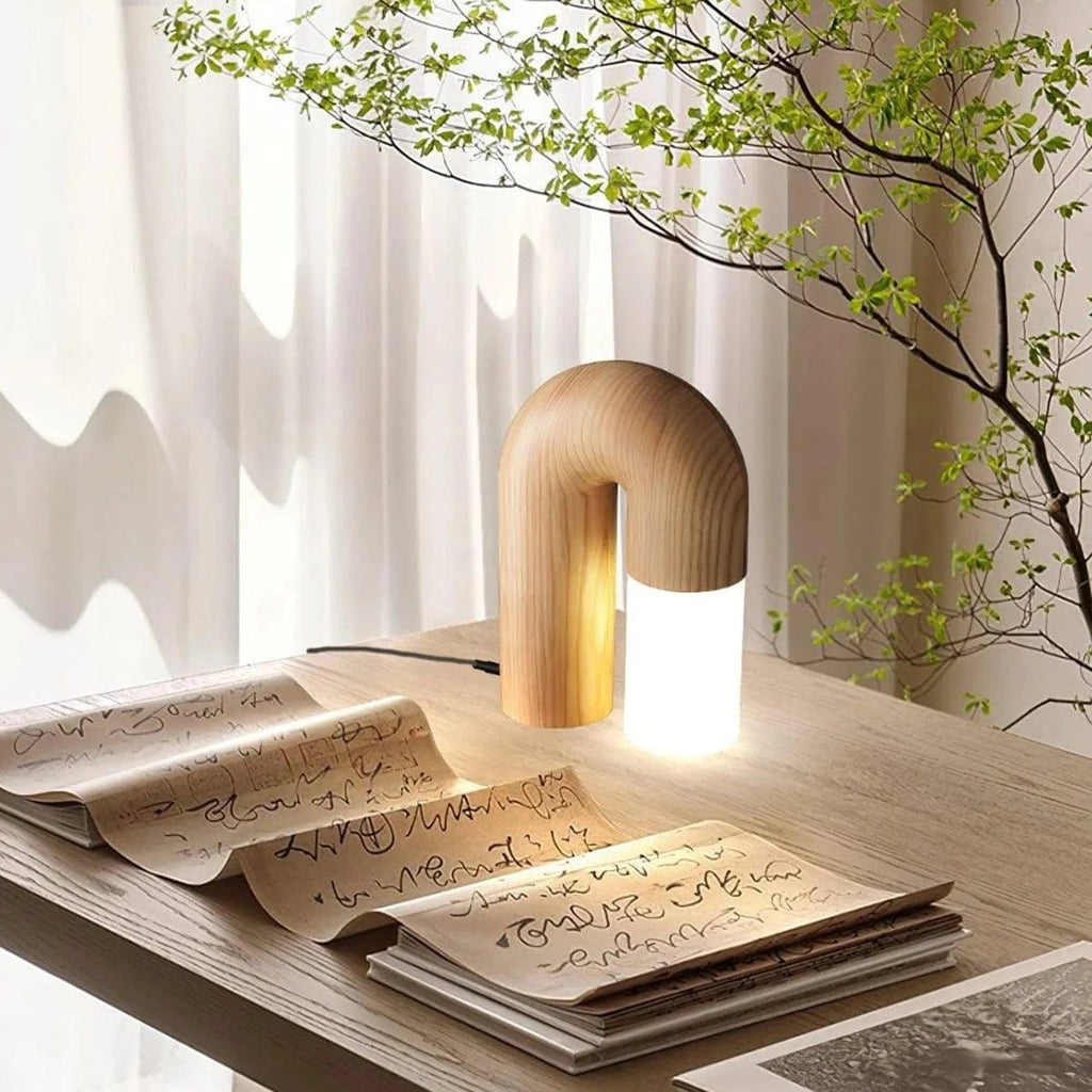 Diora table lamp lit on a desk beside an open handwritten book