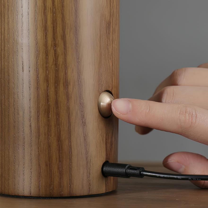 Finger pressing the brass button on the side of the Diora lamp shade