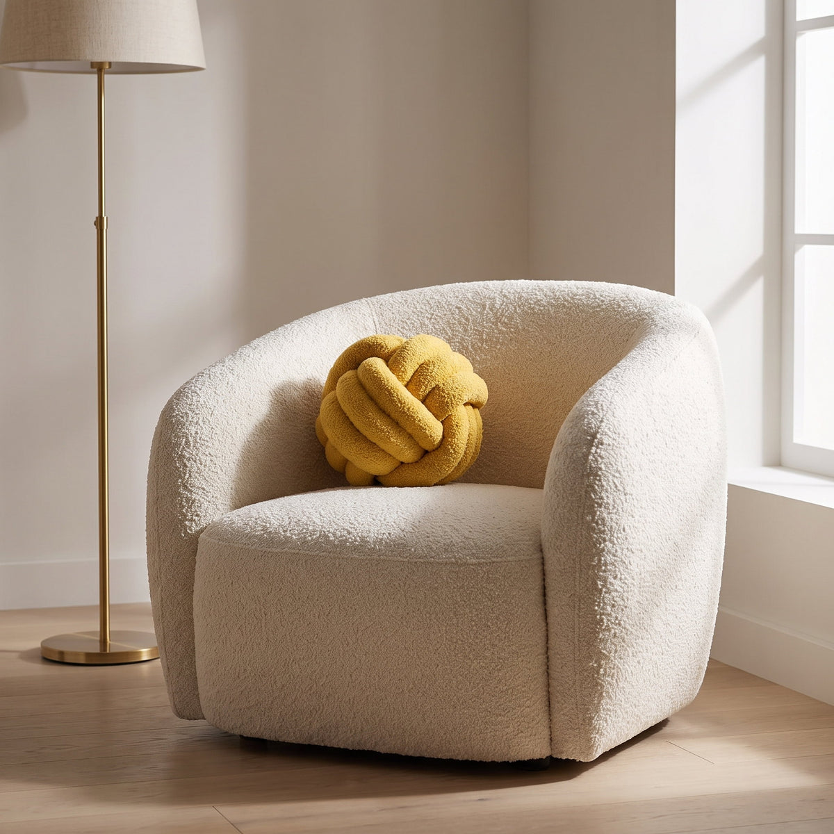 Kora yellow knotted boucle cushion on a cream boucle armchair in a reading corner