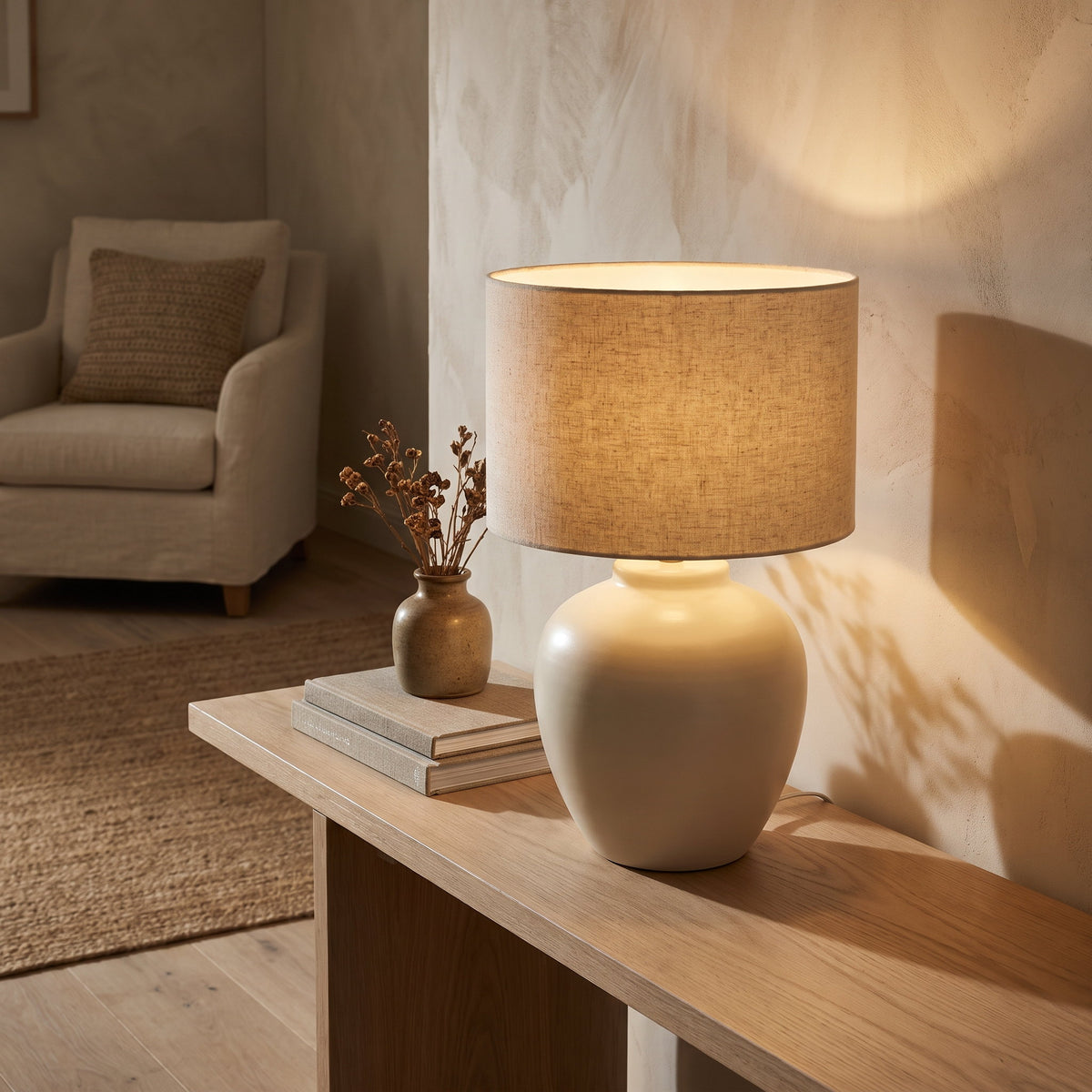 Ivory ceramic table lamp lit on an oak console in a warm sitting room, Style Room