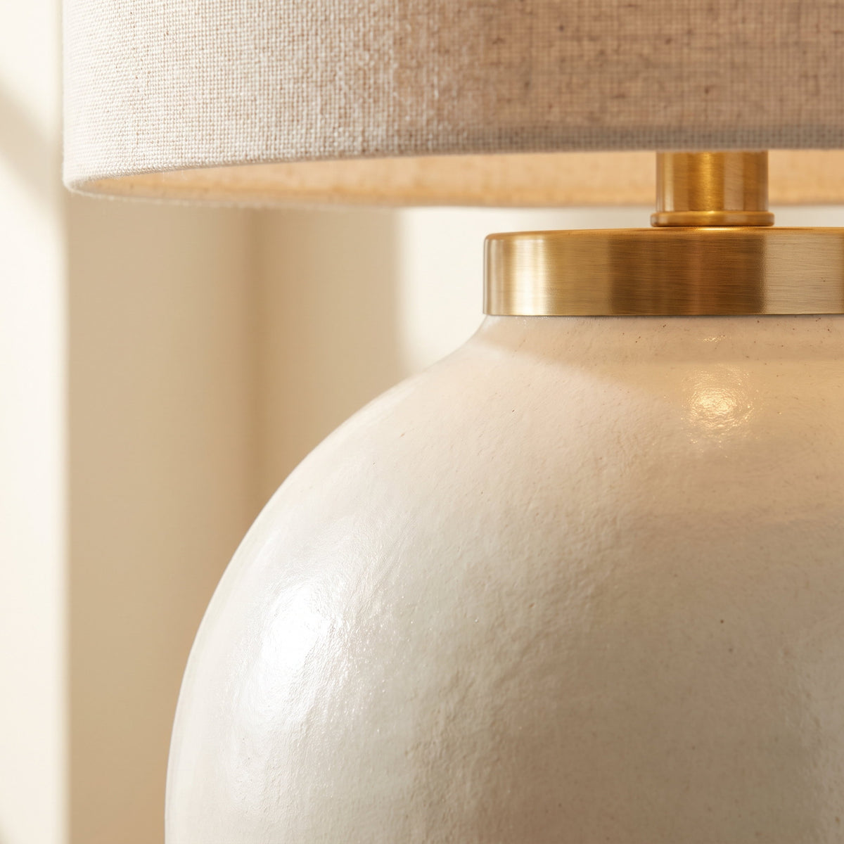 Close-up of the matte ivory glaze and brass collar on the Linnea lamp, Style Room