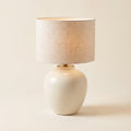 Linnea table lamp with an ivory ceramic base and a natural linen shade, front view