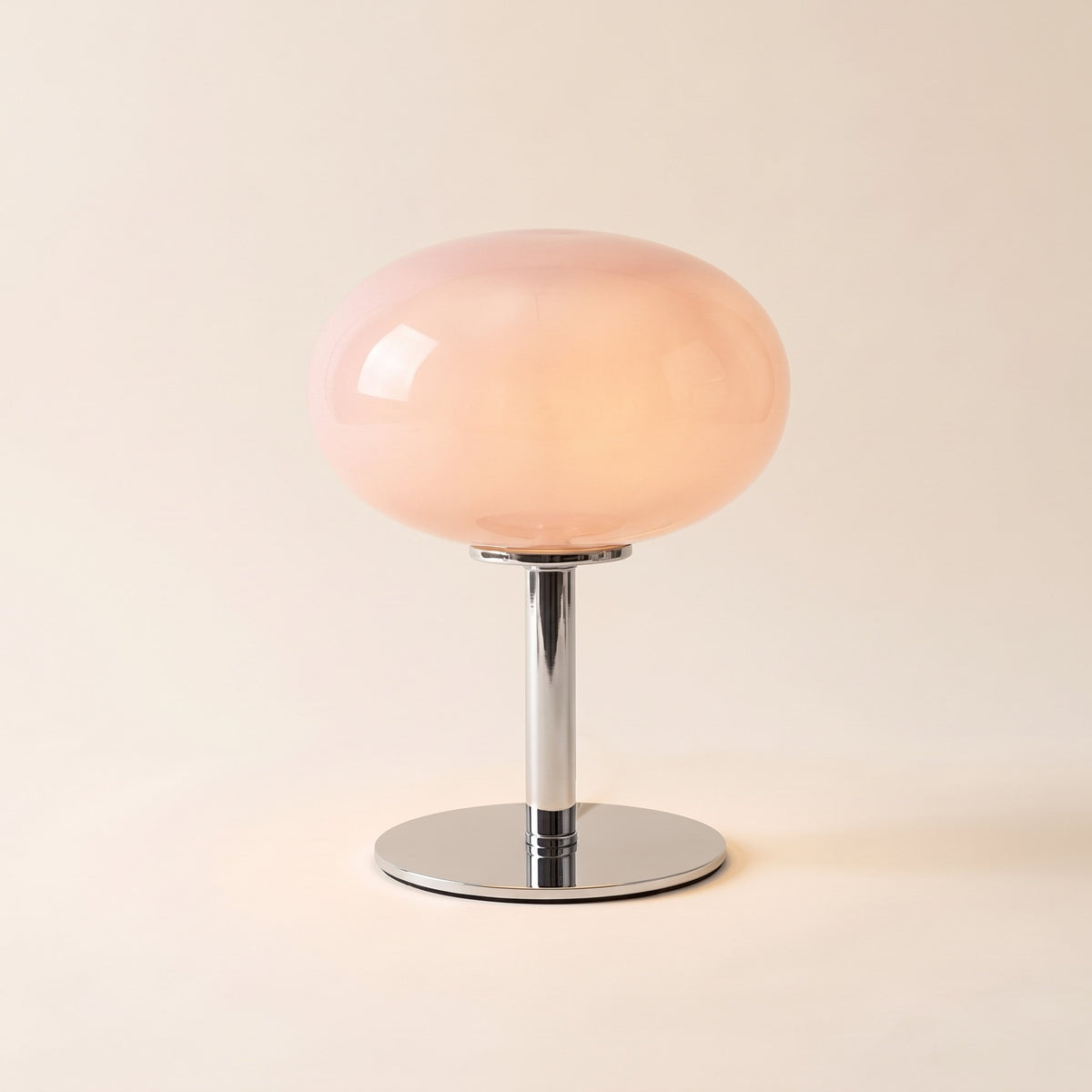 Lolly cordless table lamp with a pink glass dome, lit, on a cream background, Style Room