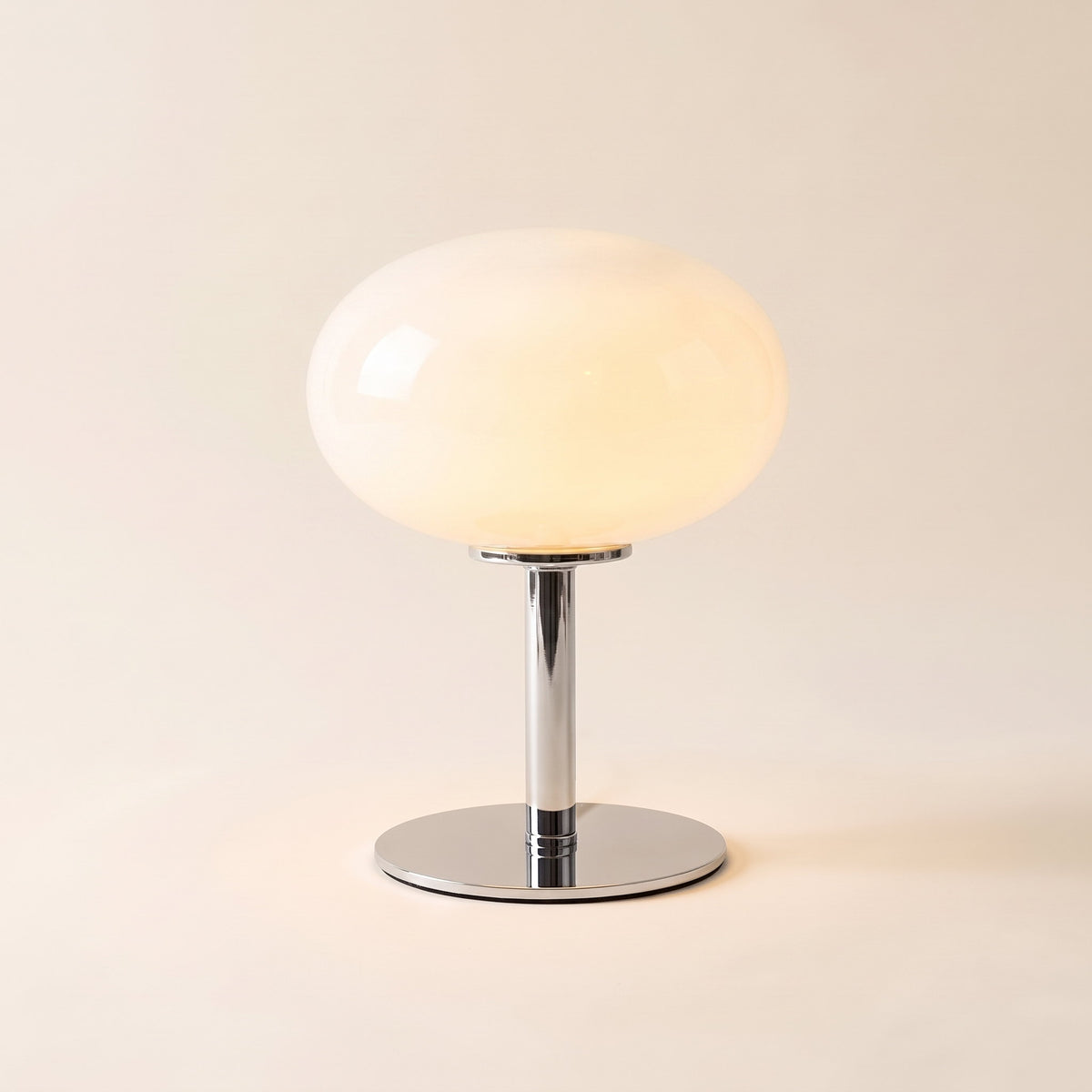 Lolly cordless table lamp with an opal white glass dome, lit, on a cream background, Style Room