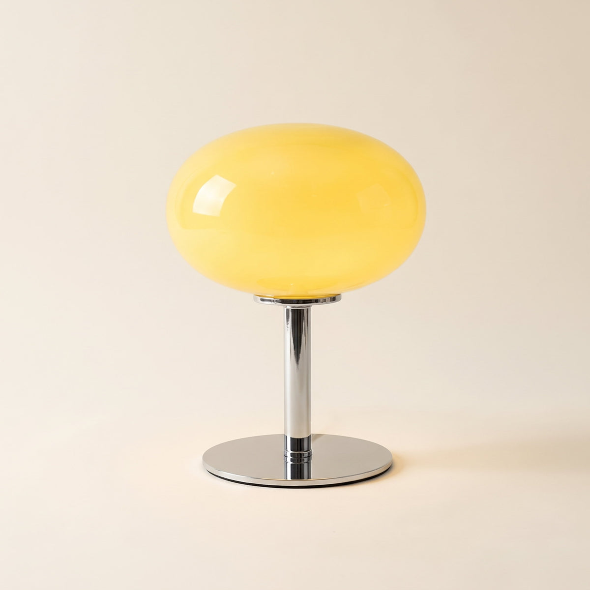 Lolly cordless table lamp with a yellow glass dome on a chrome stem, lit, on a cream background, Style Room