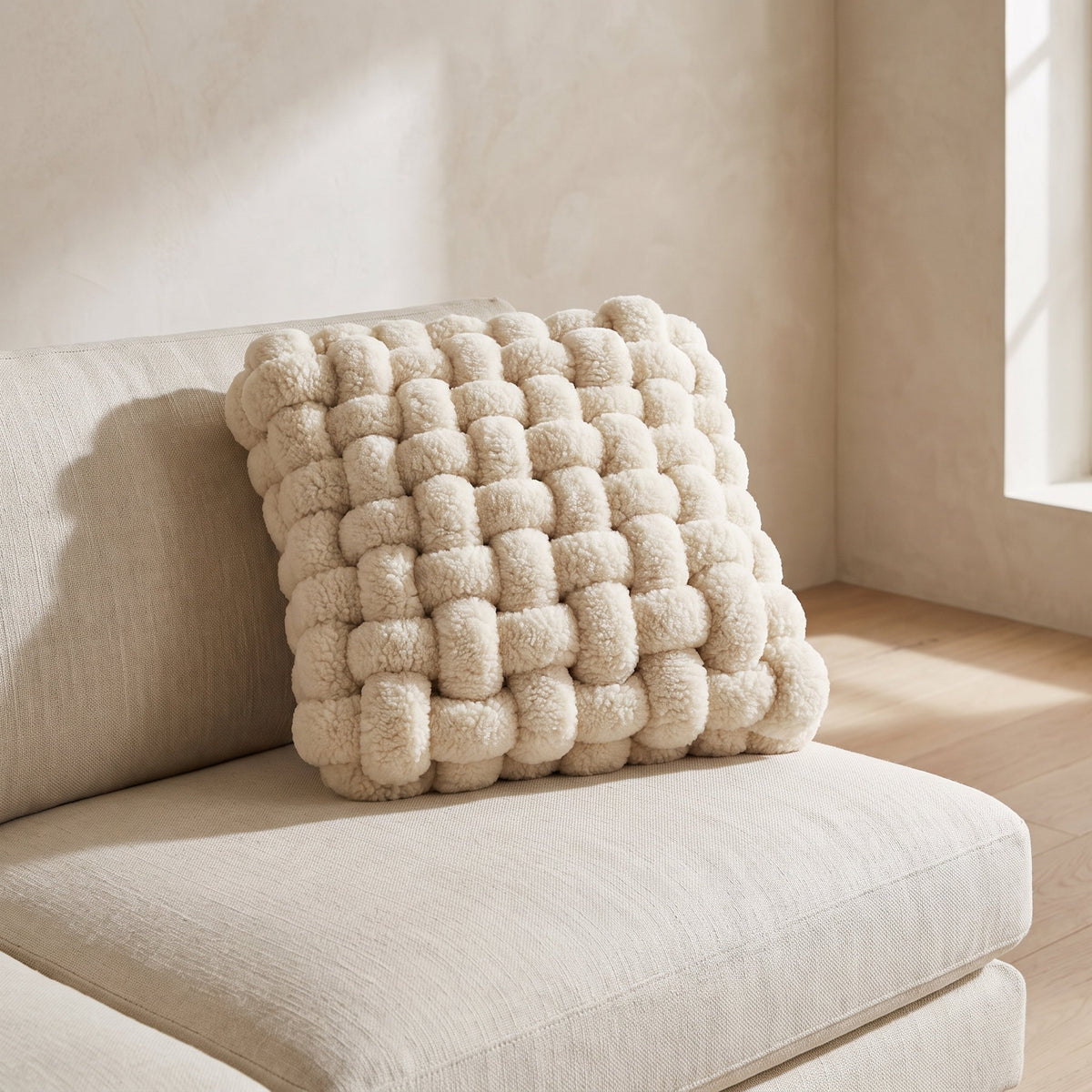 Luma woven knot cushion resting on a cream linen sofa, Style Room