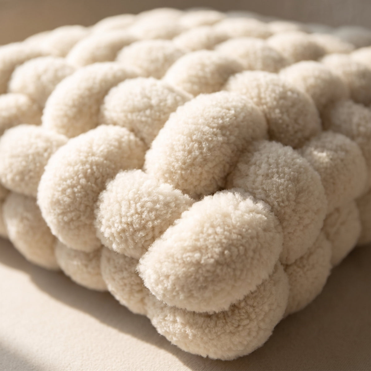 Close-up of the woven plush bobbles of the Luma knot cushion, Style Room