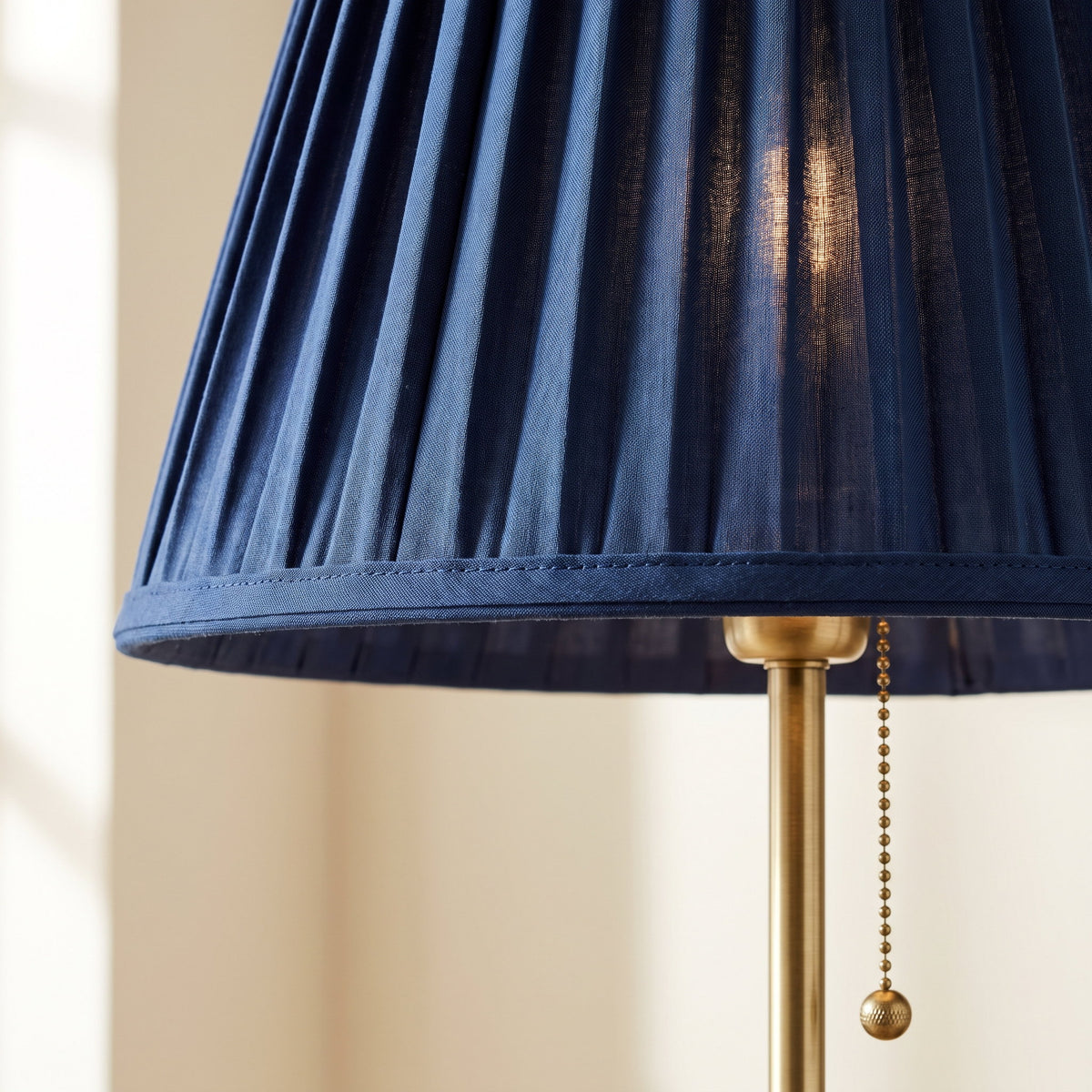 Close-up of the navy pleats and brass pull chain on the Neve lamp, Style Room