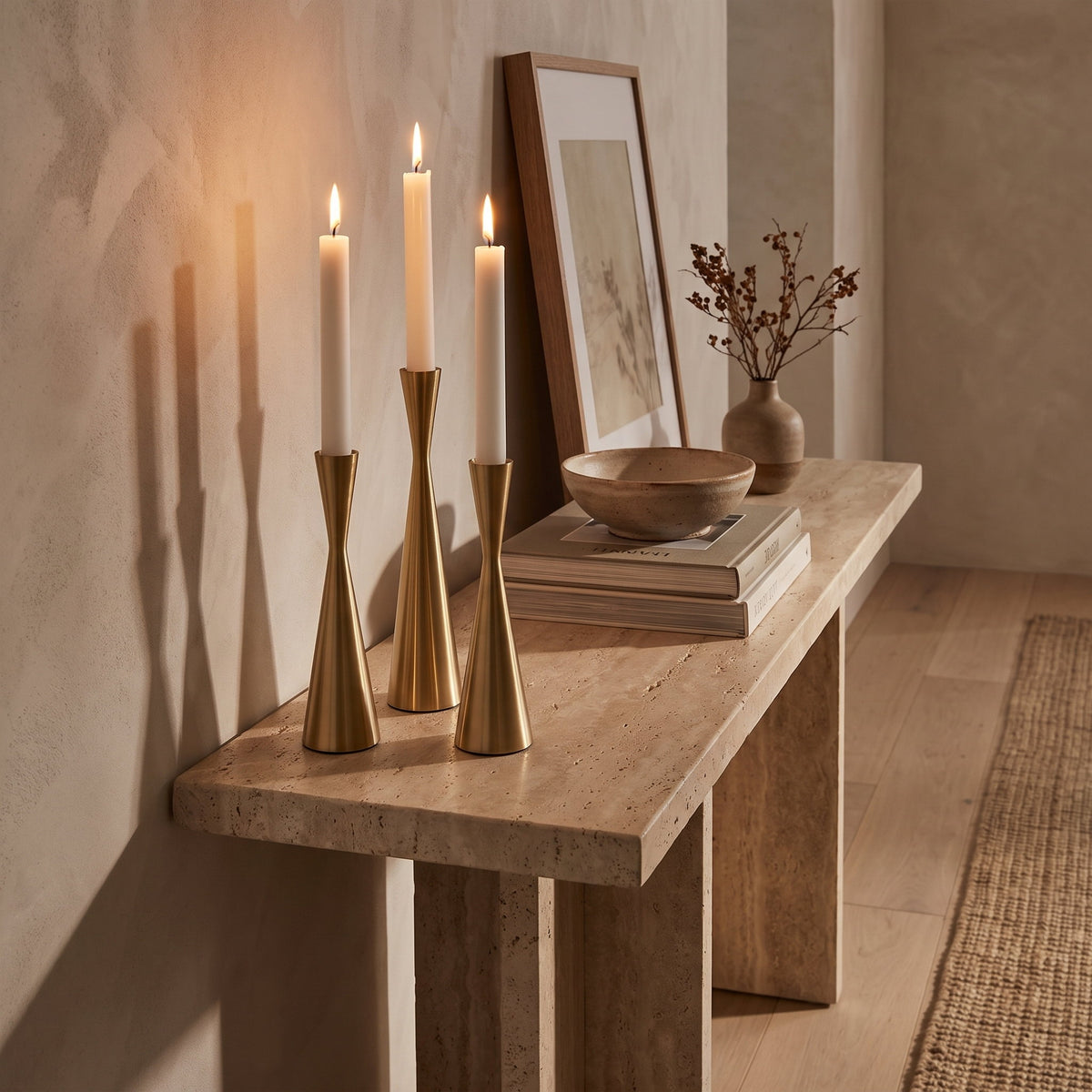 Nexa brass candlesticks lit on a travertine console, Style Room
