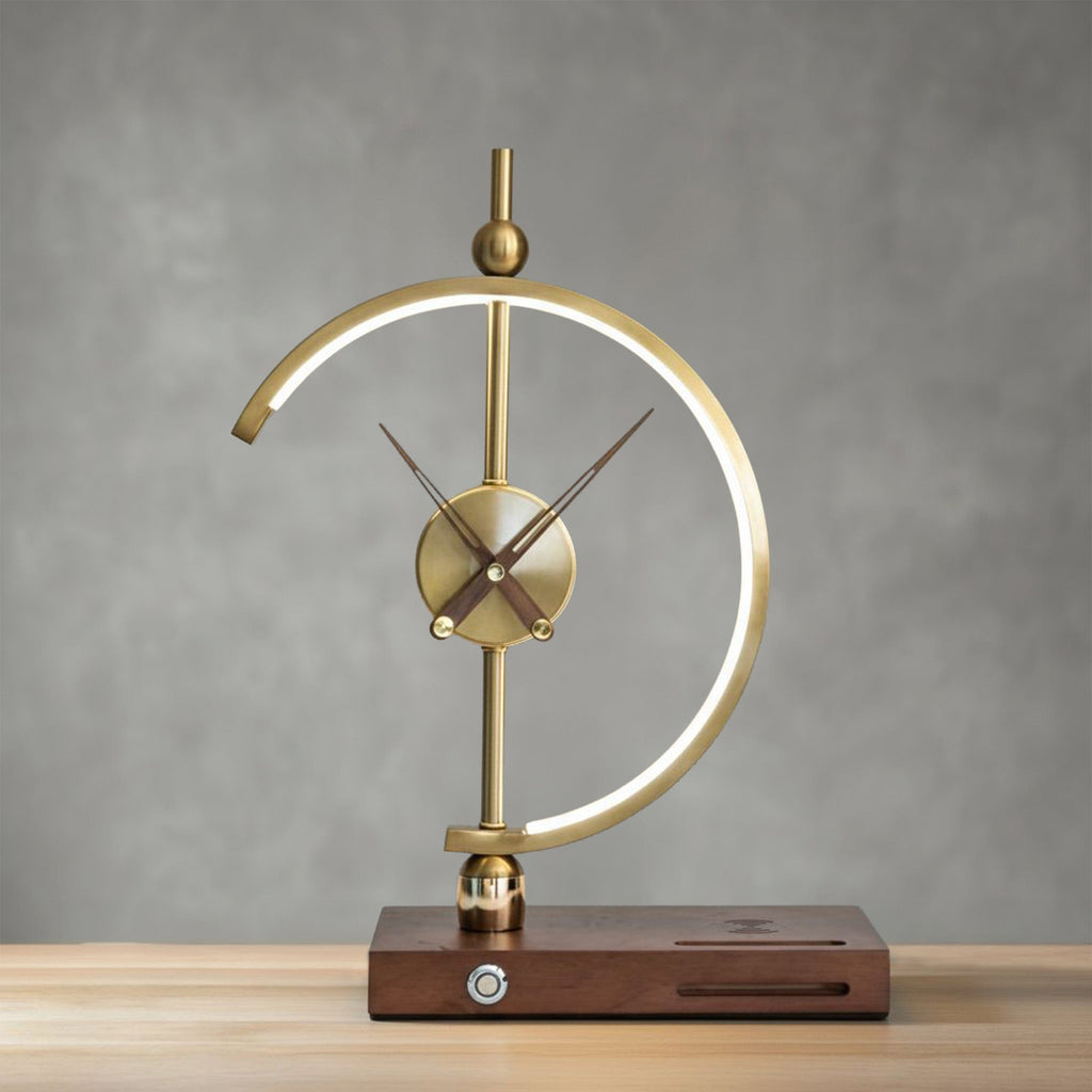 Orin clock lamp lit against a grey wall, warm glow along the inner edge of the brass arc