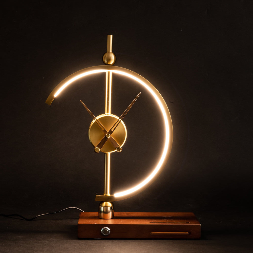 Orin clock lamp lit against a dark background with the mains cable at the rear of the walnut base