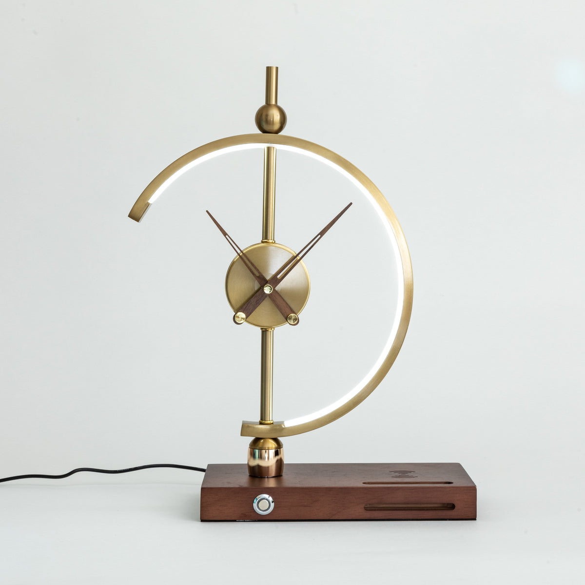 Orin clock lamp lit on a white surface, showing the walnut base, dimmer dial and mains cable