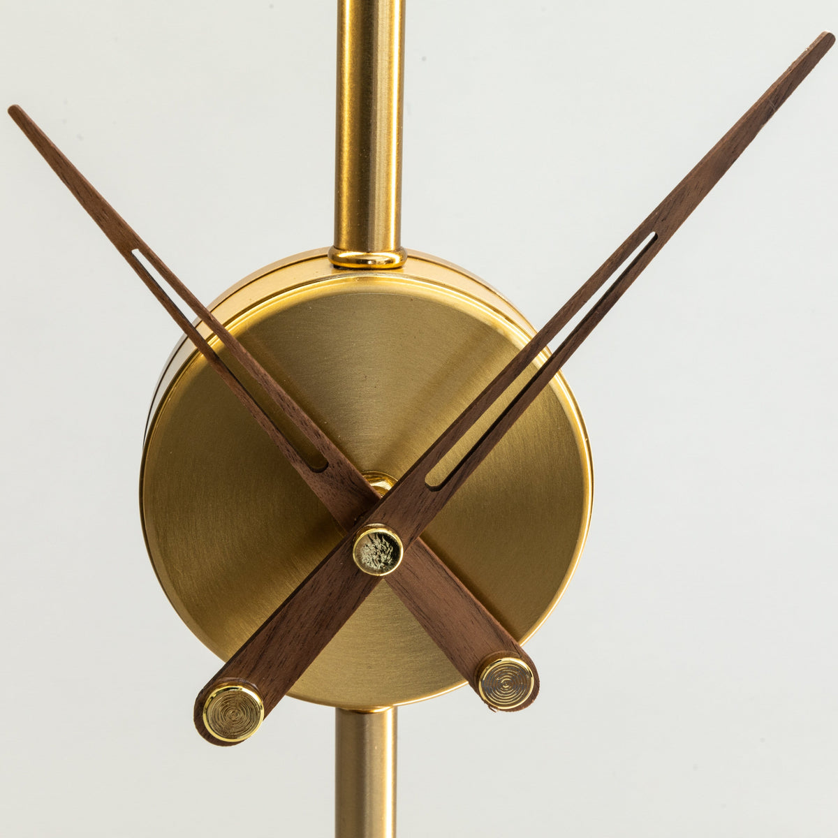 Close-up of the Orin clock face, a brushed brass disc with slender walnut hands