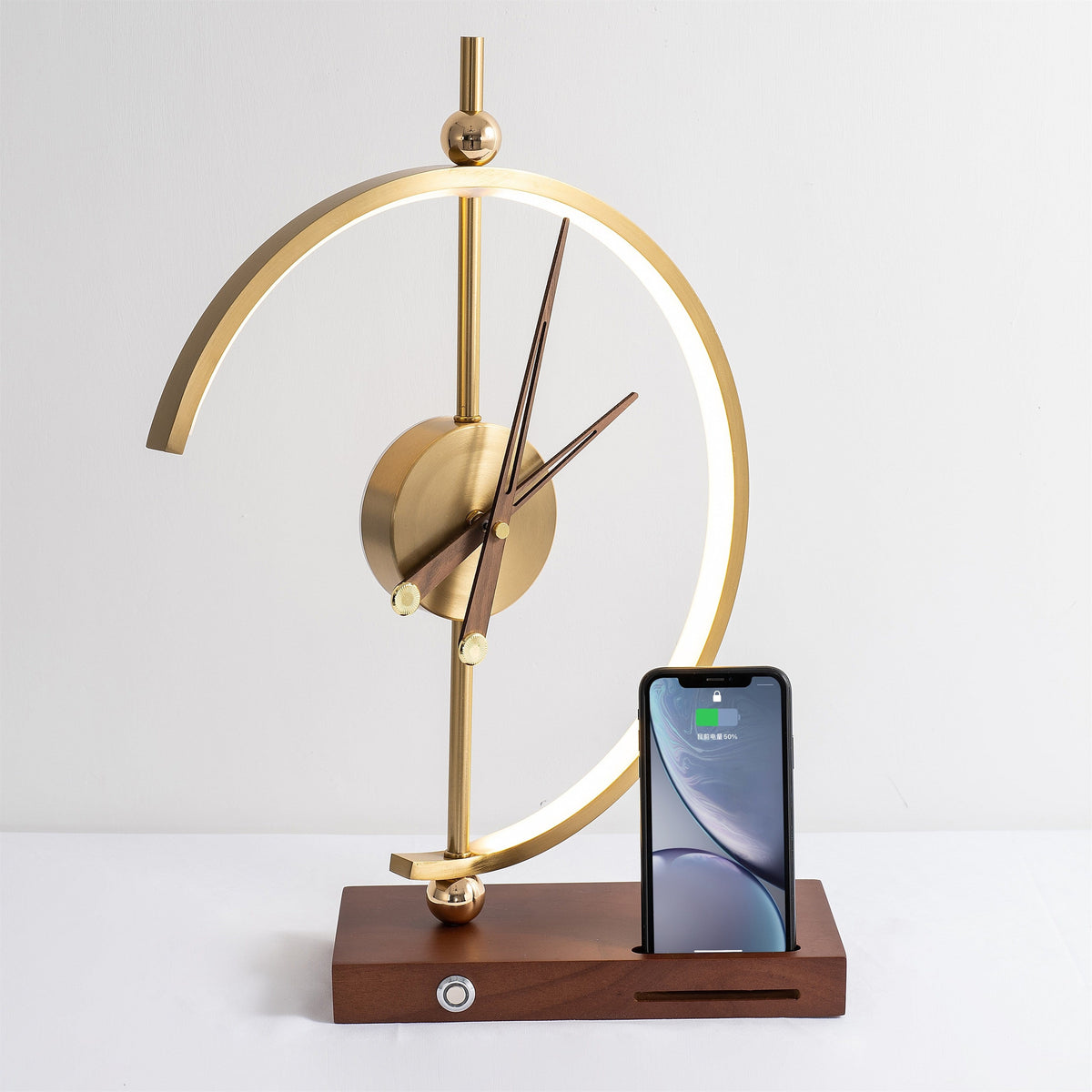 Orin clock lamp lit with a smartphone standing upright in the charging slot on the walnut base