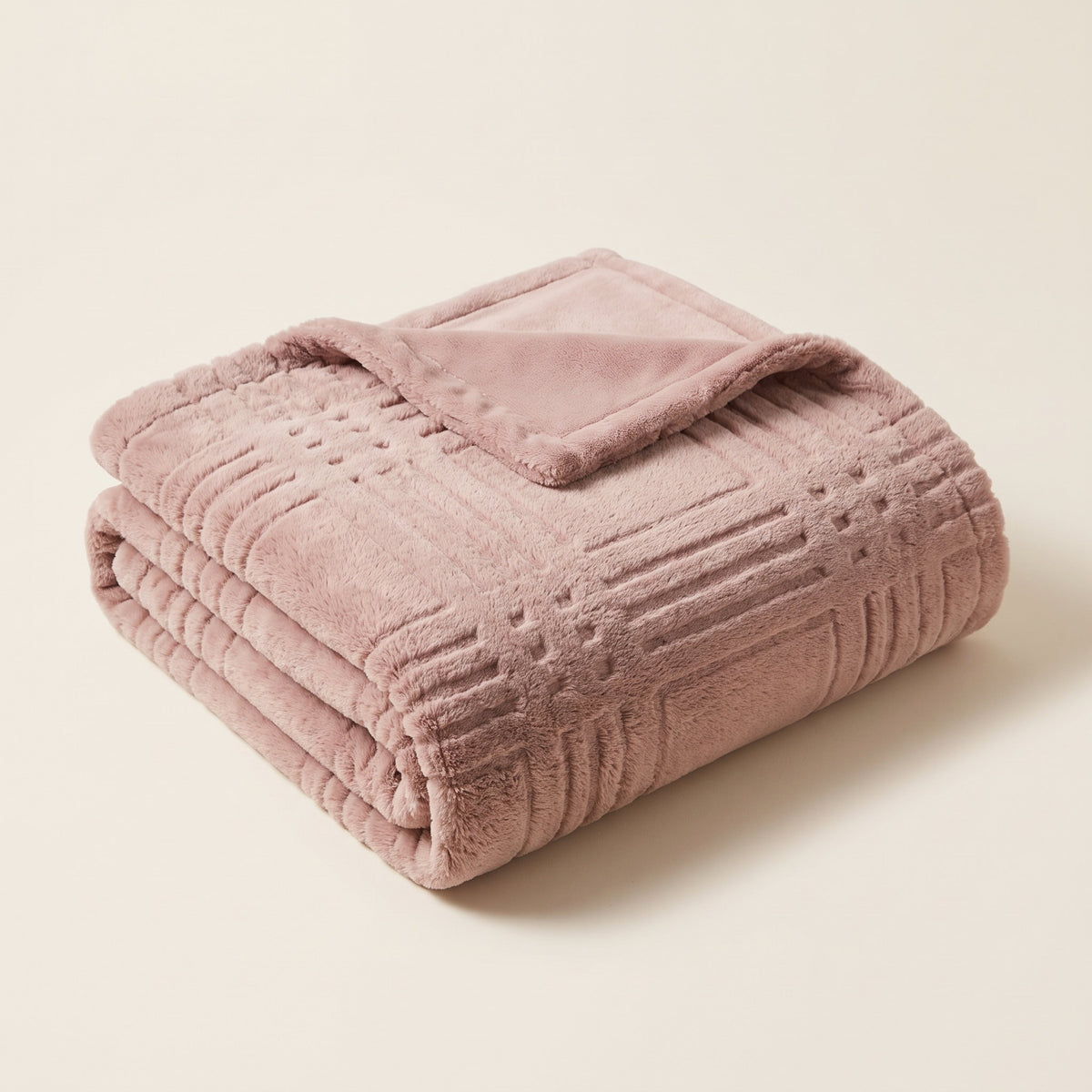 Pavo embossed grid blanket in dusty pink, neatly folded on a cream background, Style Room