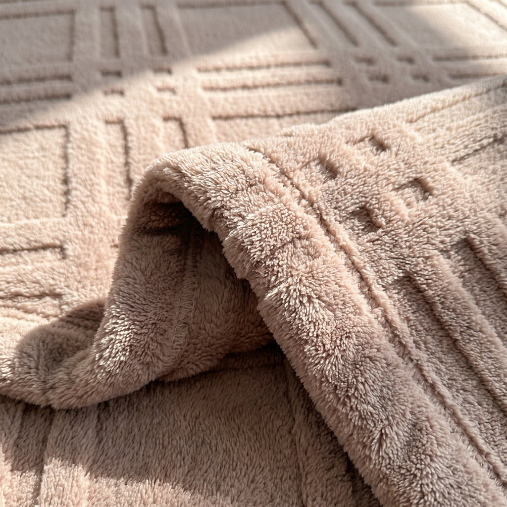 Detail of the Pavo blanket showing the embossed grid relief and plush dusty pink microfiber pile