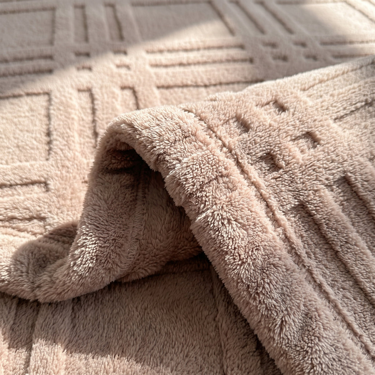 Detail of the Pavo blanket showing the embossed grid relief and plush dusty pink microfiber pile