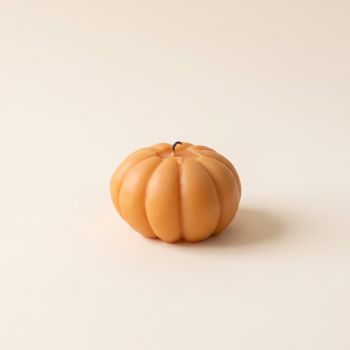 Pippin pumpkin-shaped scented candle in orange on a cream background, Style Room