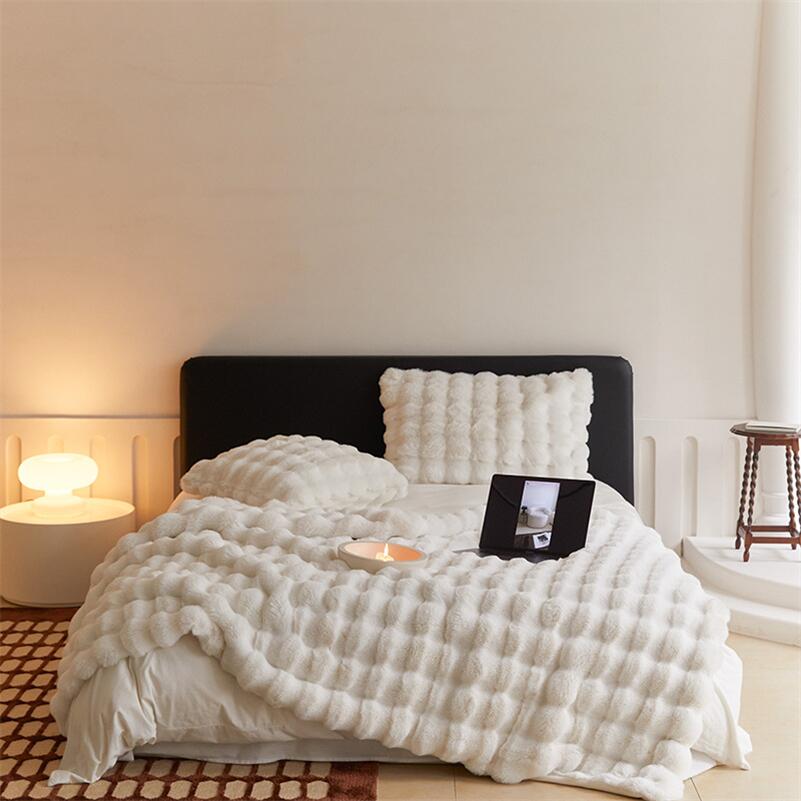 Raven throw and cushion in off-white on a bed with a black headboard