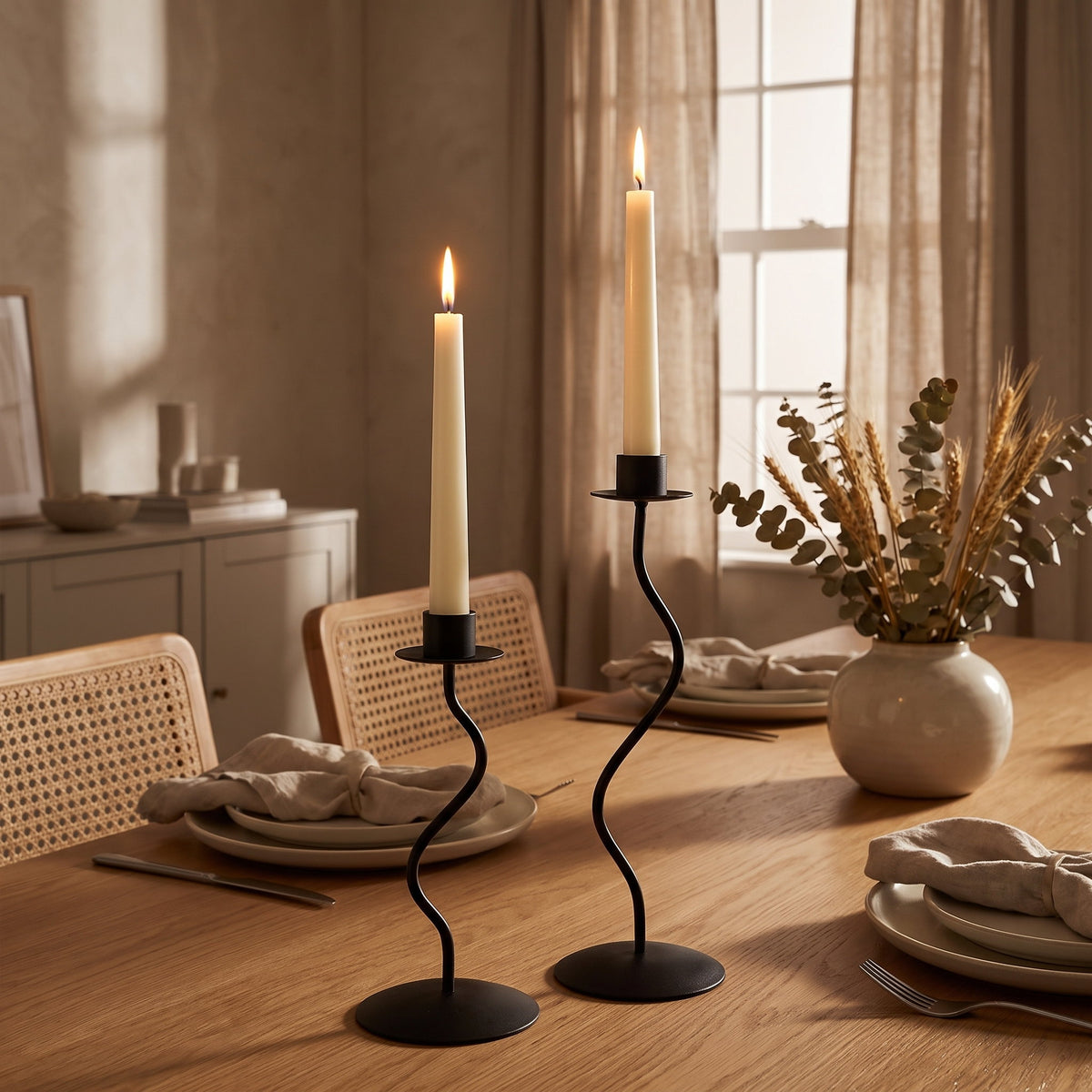 Sable wavy candle holders lit on a laid oak dining table in evening light, Style Room