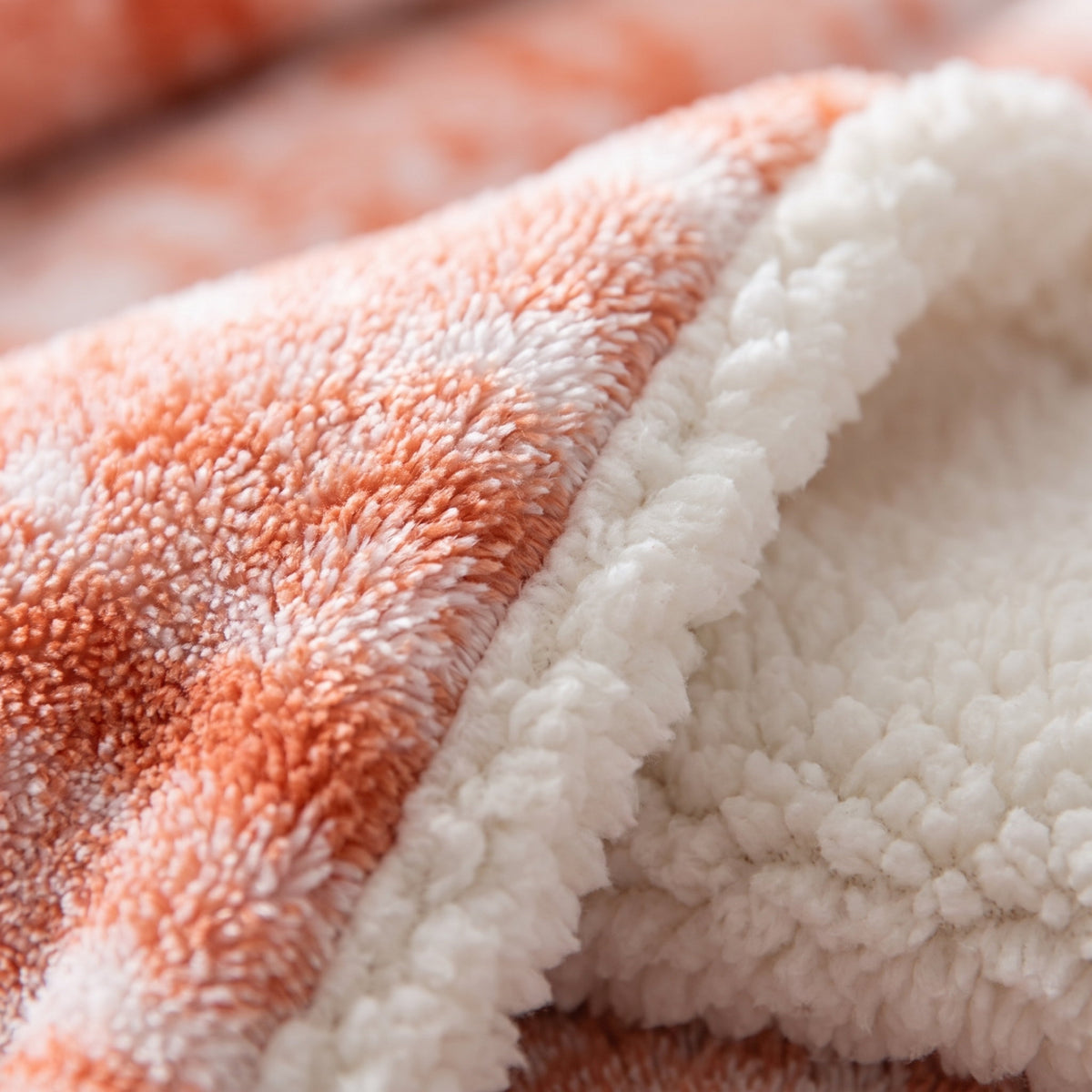 Close-up of the coral velvet face and cream sherpa reverse of the Seraphina blanket, Style Room