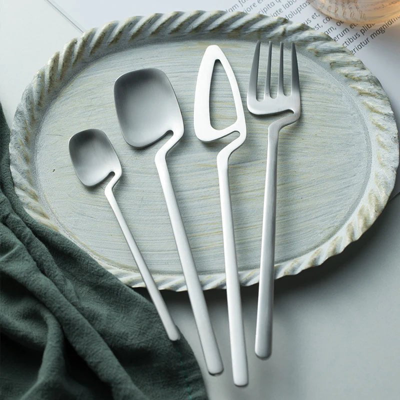 Sierra cutlery set in silver arranged on a pale ceramic plate with a green linen cloth