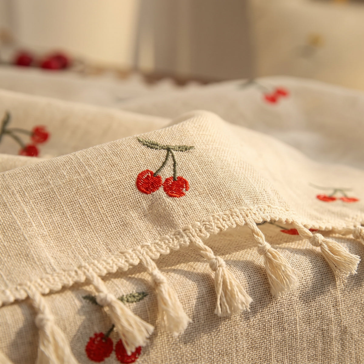 Close-up of the cherry print and tassel fringe of the Vera tablecloth, Style Room