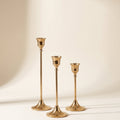 Vero brass taper candle holders, set of three graduated sizes in warm gold brass, on a cream background