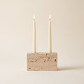 Verona travertine candle holder with two lit cream tapers, on a cream background, Style Room