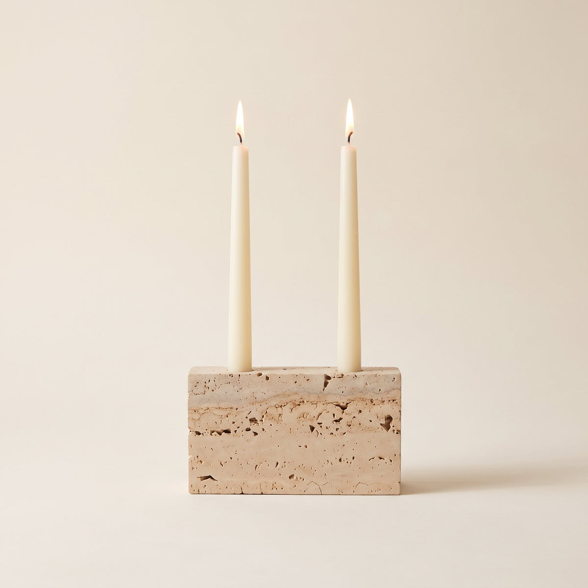 Verona travertine candle holder with two lit cream tapers, on a cream background, Style Room