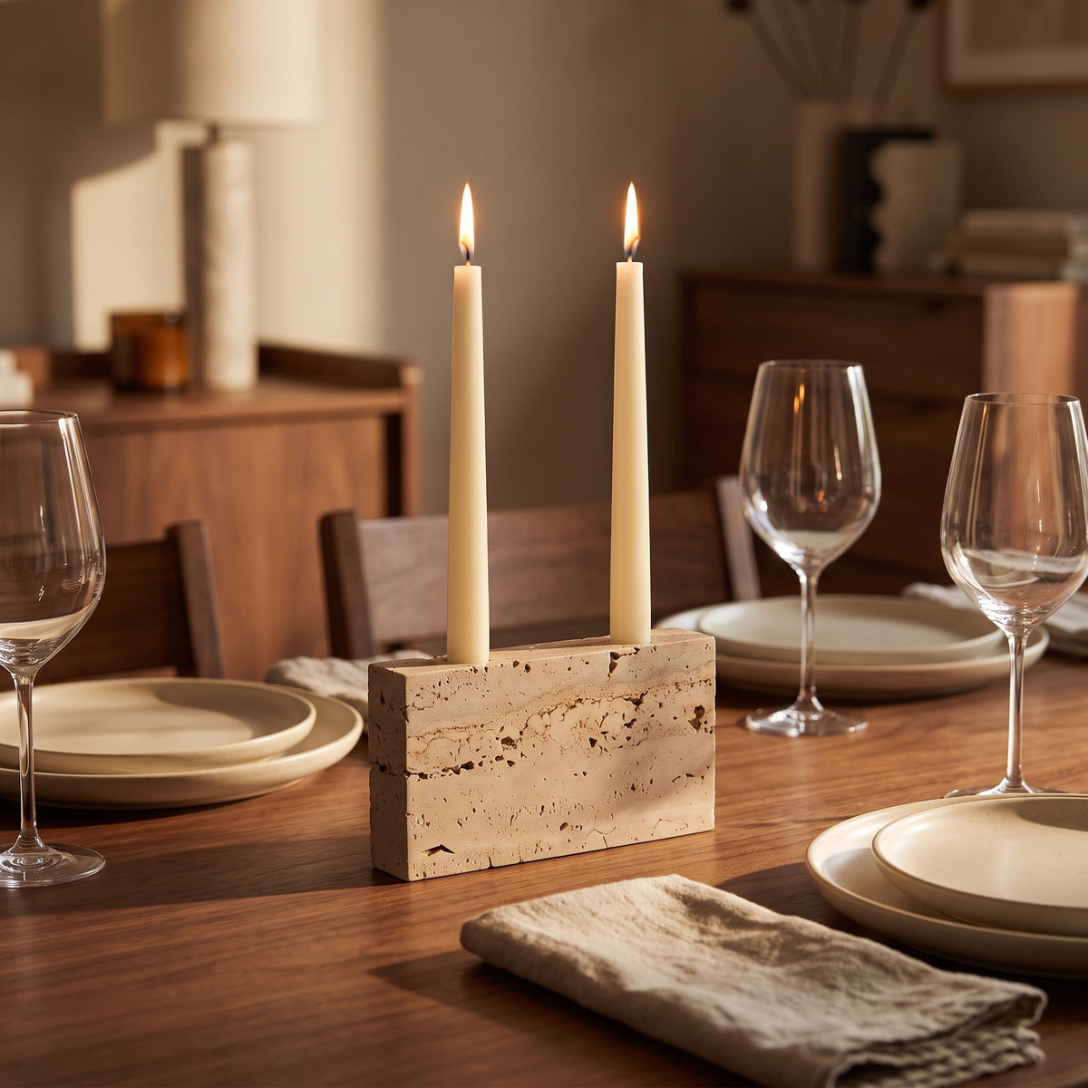 Verona travertine block with two lit tapers down the middle of a laid walnut dining table, Style Room