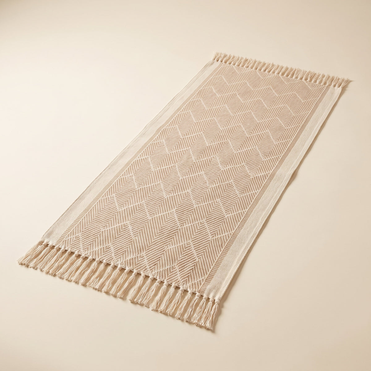 Zara woven zigzag table runner laid flat with tassels at both ends, full view