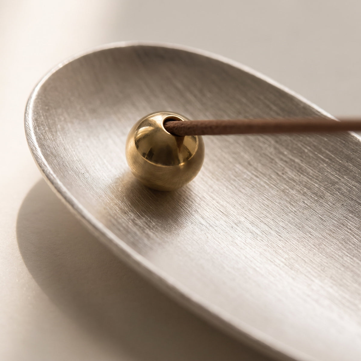 Close-up of the brass bead and brushed silver dish of the Zento holder, Style Room
